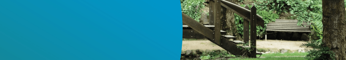 Park bench in a wooded area with a bridge in the foreground, representing the Park Bench page, for holistic care information on the PPF support space